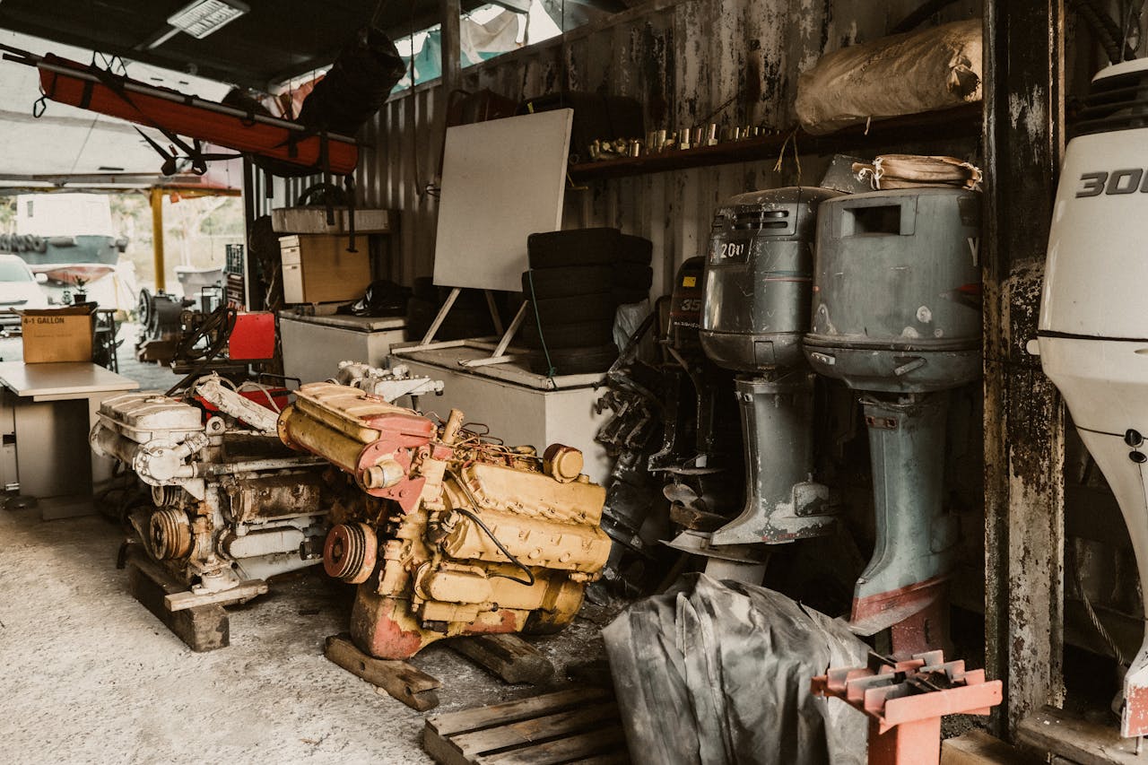 Interior of a workshop featuring engines, machinery, and outboard motors in a rustic setting.