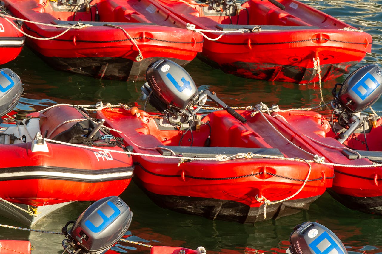 Docked red inflatable boats equipped with outboard motors, ready for use on the water.