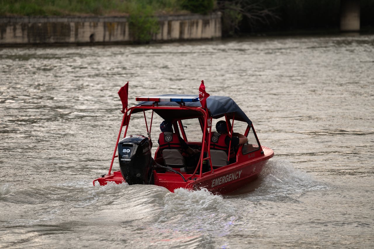 Red emergency boat navigating a river in Tbilisi, Georgia, providing water rescue services.