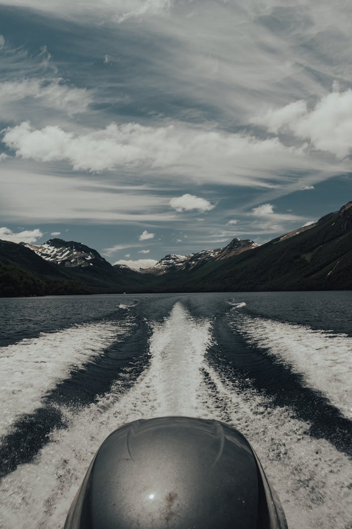 journey Explore serene mountain landscapes from a speedboat on a tranquil lake with a beautiful sky.